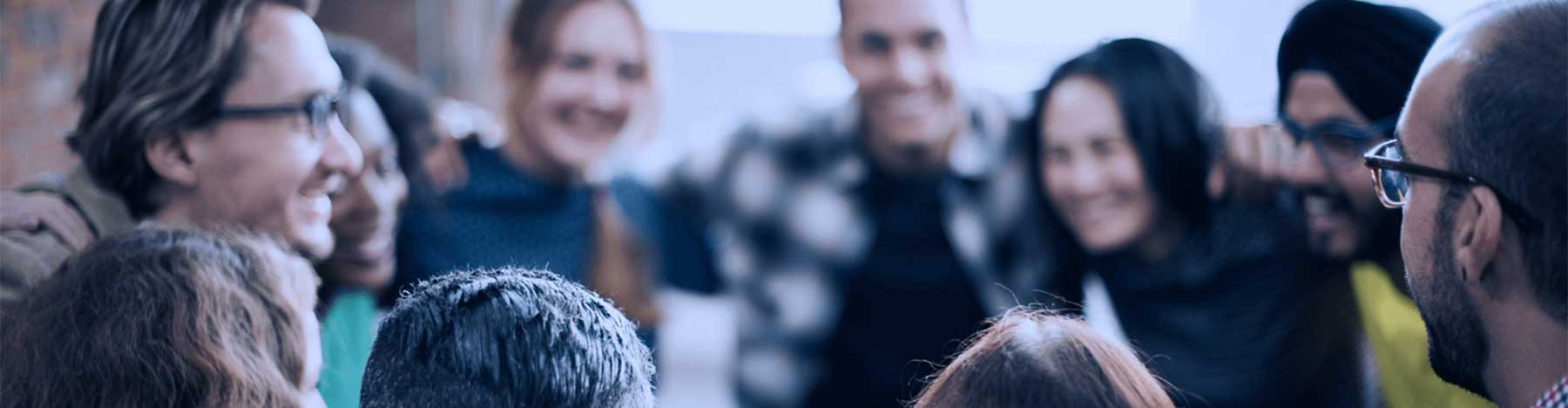 Happy group of people in a circle with arms on each other's shoulders