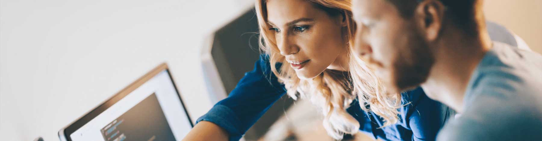 Female employee helping a co-worker at a computer screen