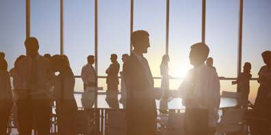 Stylized image of group of employees standing up and shaking hands around a conference table