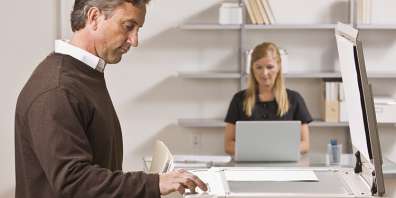 Man in foreground with woman in background working on laptop