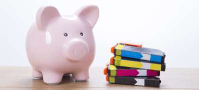 Piggy bank sitting next to a stack of toner cartridges