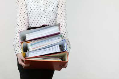 Cropped photo of woman holding a stack of thick binders