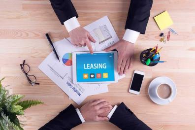 Overhead shot of a tablet in the center of a table with two business people reviewing leasing options