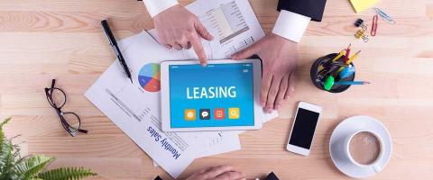 Overhead shot of a tablet in the center of a table with two business people reviewing leasing options