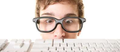 Man in over-large glasses looking down at a keyboard