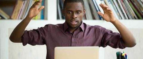 IT Professional at a laptop with his hands up as though he just made an IT mistake