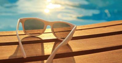 Close-up of sunglasses on a deck overlooking a pool