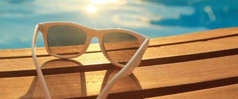 Close-up of sunglasses on a deck overlooking a pool