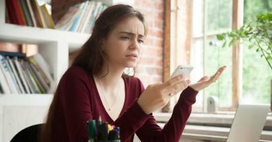 Woman looking confused staring at her cellphone to represent app-based scanners