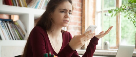 Woman looking confused staring at her cellphone to represent app-based scanners