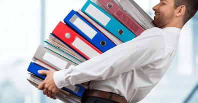 Man holding several large binders full of papers