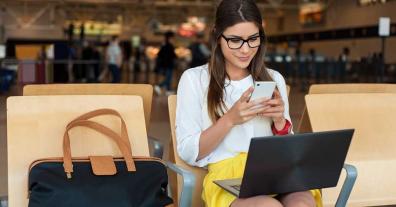 caucasian business woman in glasses on phone and laptop in an airport