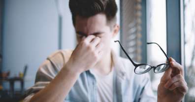 Frustrated employee rubs his eyes and holds his glasses when struggling to determine image resolution