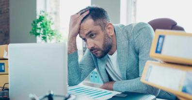 Exhausted IT worker behind a laptop representing IT burnout