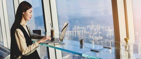 asian woman using laptop in high rise cafe