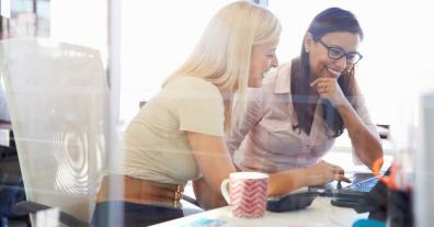 Two women working together at an office computer screen