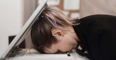 Woman with her head down on copier in exasperation