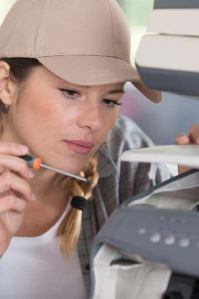 Service technician with a screwdriver fixing a printer