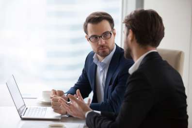 Virtual CIO meets with a potential customer and discusses options at a desk with a laptop.