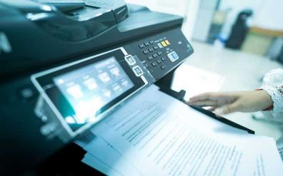 Close up of a multifunction printer's interface and documents on the output tray