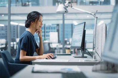 Professional businesswoman sits at an office desk starting at her computer screen signifying Managed IT Services