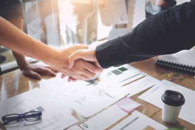 Closeup of a handshake over a conference room table in an office signifying a managed service provider agreement.