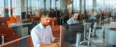 Employees in office sitting behind computer monitors enjoying work