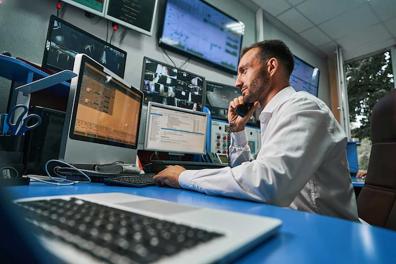 Man talking on phone and looking at multiple monitors