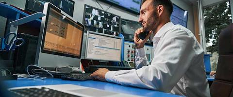 Man talking on phone and looking at multiple monitors