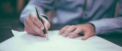 Close-up of man in dress shirt writing on a piece of paper